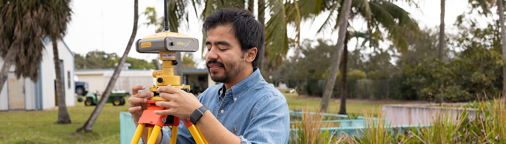 A man uses surveying equipment